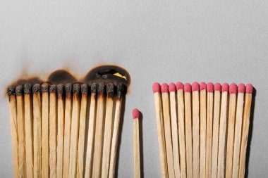 Burnt and whole matches on light grey background, flat lay