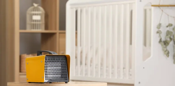 Modern electric fan heater on coffee table in cozy room
