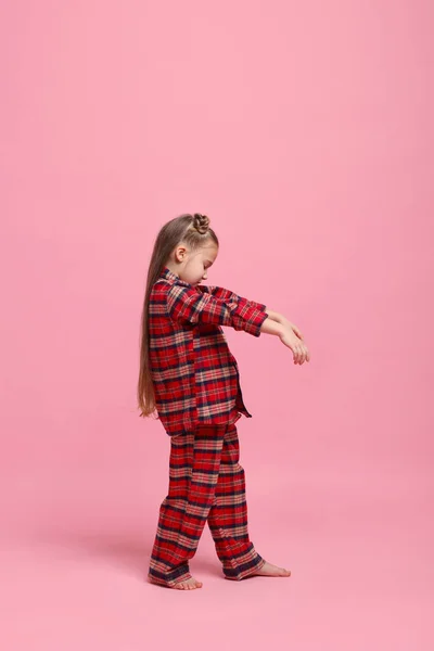 Girl in pajamas sleepwalking on pink background