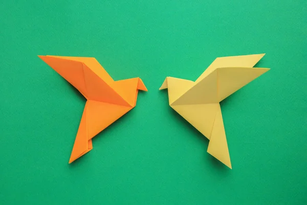 Beautiful colorful origami birds on green background, flat lay