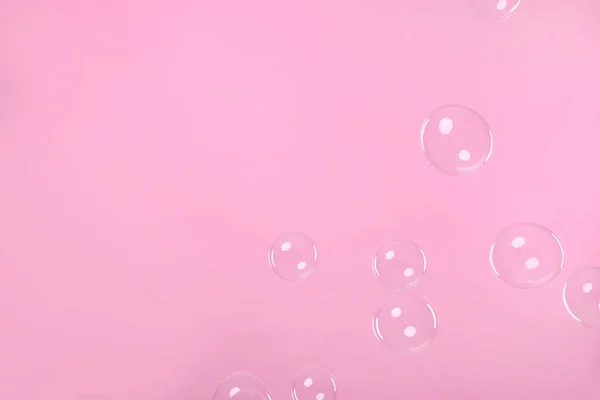 Many beautiful soap bubbles on pink background. Space for text