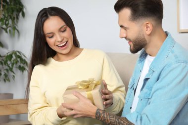 Man presenting gift to his girlfriend at home