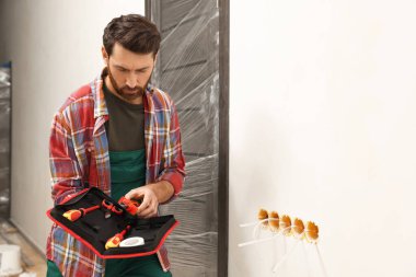 Electrician taking pilers from tool bag indoors