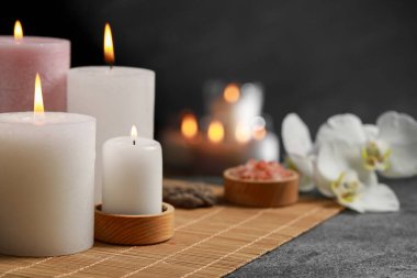 Beautiful spa composition with burning candles on dark grey table. Space for text