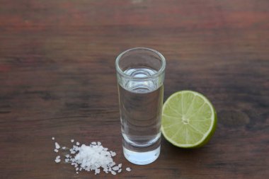 Mexican tequila shots with lime and salt on wooden table