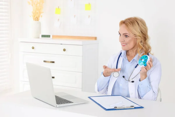 Doctor with laptop and pills consulting patient in clinic. Online medicine concept