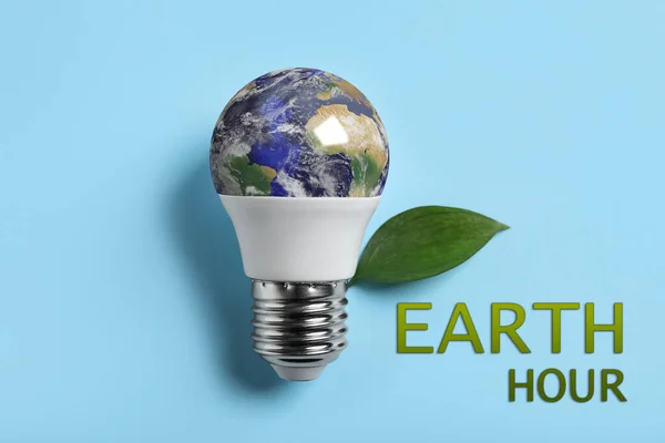 Take care of environment. Light bulb with globe, green leaf and words Earth hour on light blue background, top view