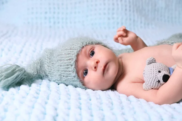 Cute newborn baby with crochet toy on light blue blanket
