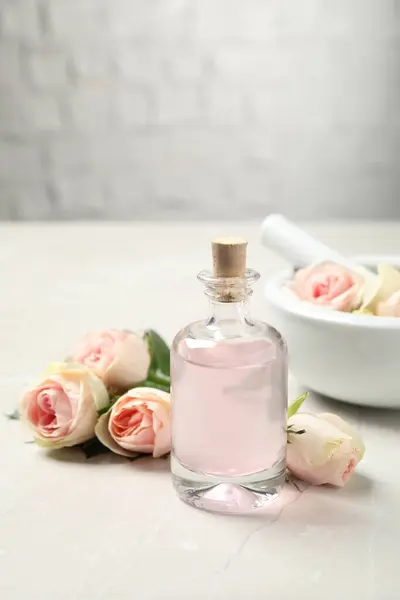 白いテーブルの上にバラの精油と花のボトル — ストック写真