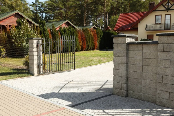 Open metal gates near houses and bushes outdoors