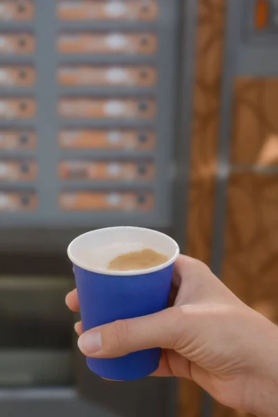 Woman holding paper cup with coffee near vending machine, closeup