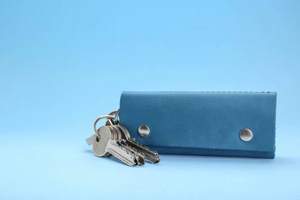 Leather case with keys on light blue background. Space for text