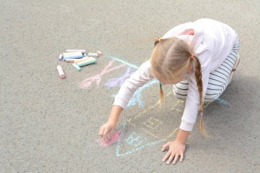 Little child drawing happy family with chalk on asphalt