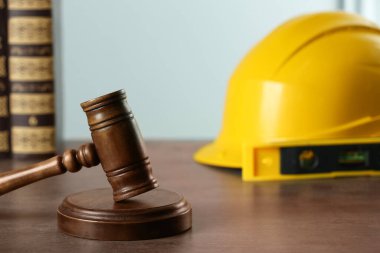 Construction and land law concepts. Judge gavel, books, level with hardhat on grey table, space for text