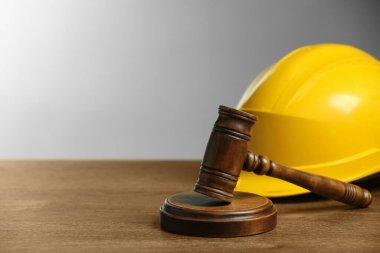 Construction and land law concepts. Gavel and hard hat on wooden table, space for text