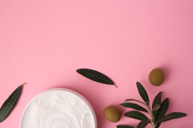 Natural cosmetic. Olive cream and ingredient on pink background, flat lay. Space for text