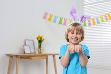 Happy boy wearing bunny ears indoors, space for text. Easter celebration