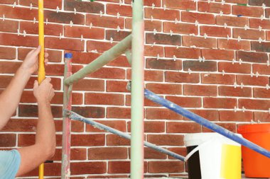 Professional builder working near brick wall, closeup. Tiles installation process