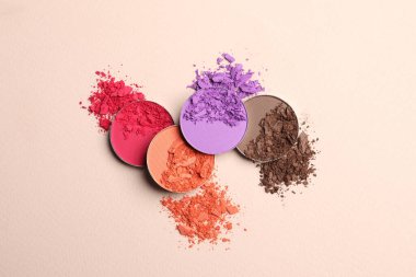 Different crushed eye shadows on beige background, flat lay