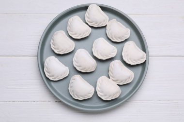 Raw dumplings (varenyky) on white wooden table, top view