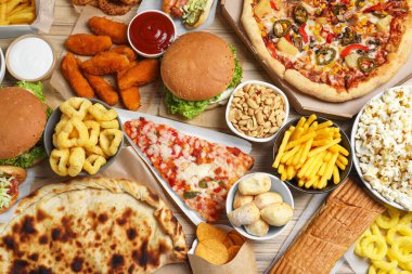 French fries, pizza and other fast food on wooden table, flat lay