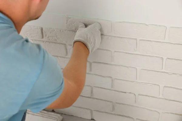 Worker installing decorative wall tiles in room, closeup