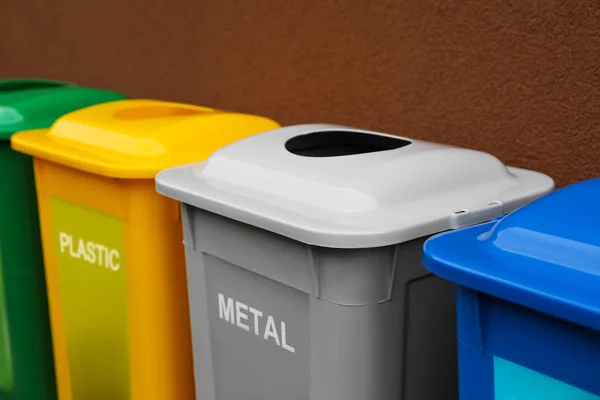 Many color recycling bins near brown wall, closeup