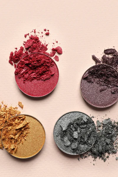 Different crushed eye shadows on beige background, flat lay