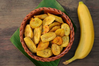 Lezzetli kızarmış muz dilimleri ve ahşap masada taze meyve.
