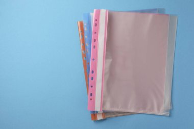 File folders with punched pockets on light blue background, flat lay. Space for text