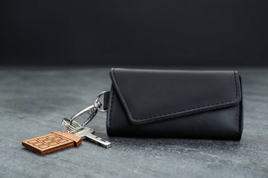 Leather case with key on grey table, closeup