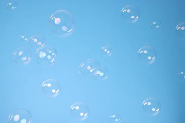 Many beautiful soap bubbles on light blue background. Space for text