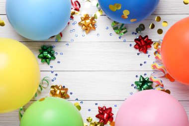 Flat lay composition with balloons and confetti on white wooden table, space for text. Birthday celebration