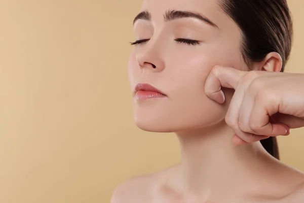 Young Woman Massaging Her Face Beige Background Space Text — Fotografia de Stock