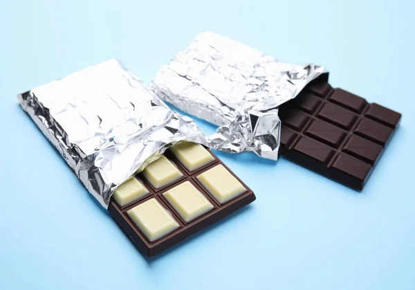 Tasty chocolate bars on light blue background