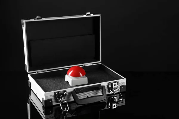 Red button of nuclear weapon in suitcase on black background, space for text. War concept