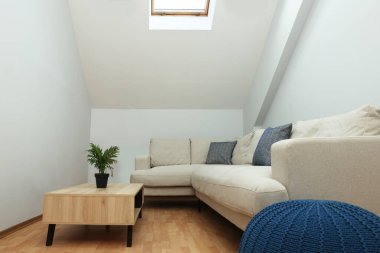 Çatı katı içi eğimli tavan ve mobilyalarla dolu.