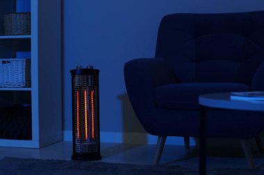 Geceleri karanlık oturma odasında elektrikli kızılötesi ısıtıcı.