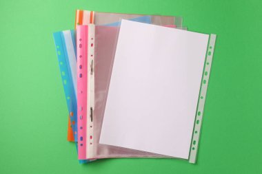 File folders with punched pockets on green background, flat lay