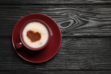 Siyah ahşap masa üzerinde kalp şeklinde süslemeli bir fincan aromatik kahve, üst manzara. Metin için boşluk