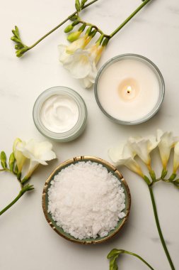 Flat lay composition with different spa products and flowers on white marble table
