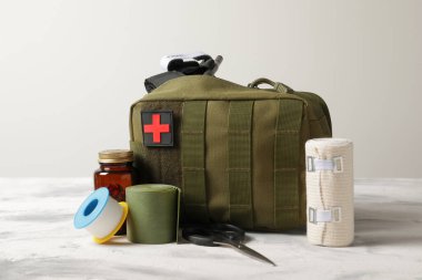 Military first aid kit, tourniquet, pills and elastic bandage on light grey table