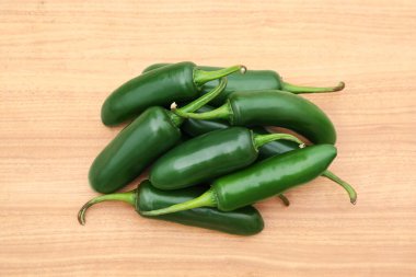 Pile of fresh ripe green jalapeno peppers on wooden table