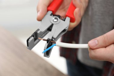 Professional electrician stripping wiring indoors, closeup view