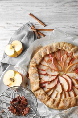 Delicious apple galette, cinnamon and pecans on table, flat lay