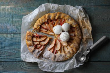 Delicious apple galette with ice cream and pecans on wooden table, flat lay