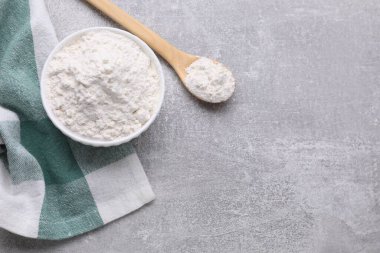 Bowl and spoon with bean flour on light grey table, flat lay. Space for text