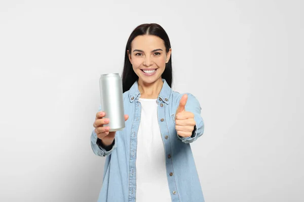 美しい幸せな女性保持飲料缶と上の親指を表示ライトグレーの背景 — ストック写真
