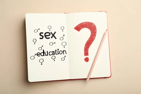 Notebook with text Sex Education, question mark, female and male gender signs on beige background, top view