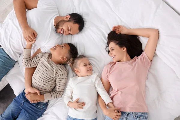 stock image Happy international family lying on bed, top view